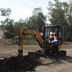 JCB Digger digging a trench-Man wearing high-vis jacket